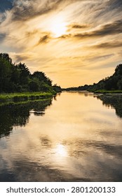 a landscape with the setting sun over the Bug River in summer