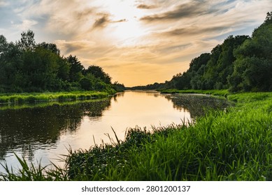 a landscape with the setting sun over the Bug River in summer