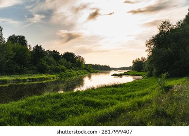 a landscape with the setting sun over the Bug River in summer