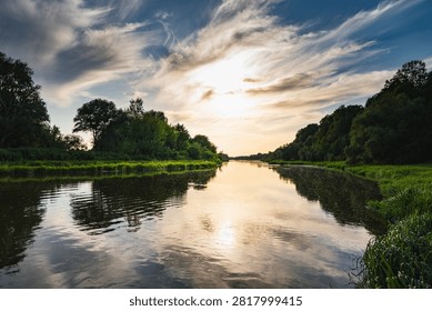 a landscape with the setting sun over the Bug River in summer