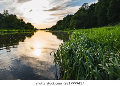 a landscape with the setting sun over the Bug River in summer