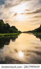 a landscape with the setting sun over the Bug River in summer