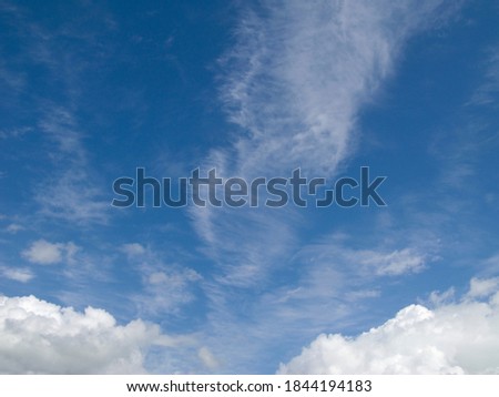 Landscape shot with wind turbines between fields and four flying cranes in front of a blue sky