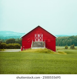 landscape showing a red wooden barn in norway standing alone in a field with mountains and trees in the background - Powered by Shutterstock