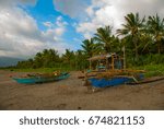 Landscape sky with clouds, mountains in cloudy weather. The volcanic sandy beach with boats. Pandan, Panay island, Philippines.