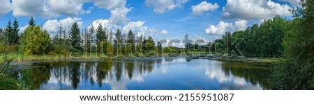 landscape with small pond surrounded by trees with sky reflection
