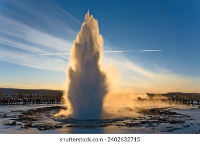 A landscape of Strokkur fountain snowy glacier lake water in Iceland at with sunrise sky