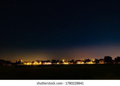 Landscape Of A Suburb Neighborhood And The Night Sky Above.