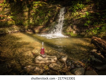 Landscape at a summer waterfall with a bottle in the form of a violin