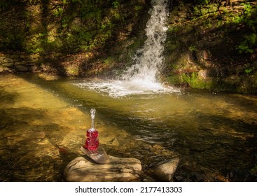 Landscape at a summer waterfall with a bottle in the form of a violin
