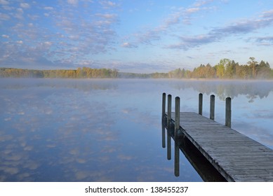 Landscape At Sunrise Of Dock, Spring Shoreline Of Whitford Lake, And Reflections In Calm Water , Fort Custer State Park, Michigan, USA