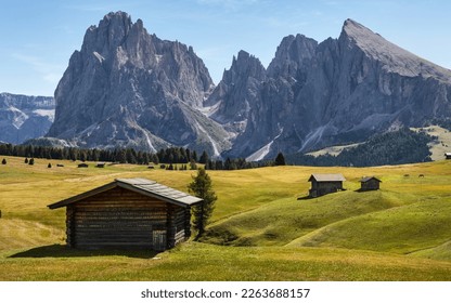 Landscape with a traditional wooden huts on Alpe di Siusi (Seiser Alm) with Sassolungo (Langkofel) in the background. Breathtaking scenic panoramic view of vibrant green rolling hills. Dolomites. - Powered by Shutterstock