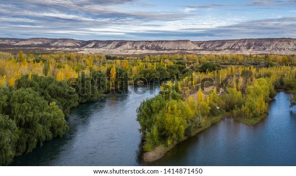 Landscape of a valley in autumn. There is a\
huge river divided in two and big mountain cliffs behind. General\
Roca, Río Negro - Patagonia\
Argentina