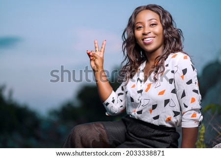 landscape view of beautiful african lady, with a two sure sign, cheerful black woman outdoor 