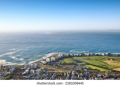 Landscape view of a beautiful coastal city near the beach on a summer day. Aerial view of a popular tourist urban town with greenery and nature during summer. Top view ocean and residential buildings - Powered by Shutterstock