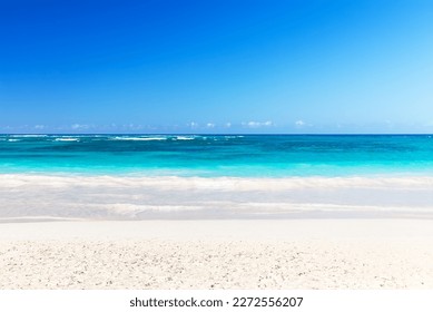 Landscape view of beautiful tropical white sand beach and turquoise sea in sunny day in Punta Cana, Dominican Republic. Empty tropical beach background. Horizon with sky and white sand.