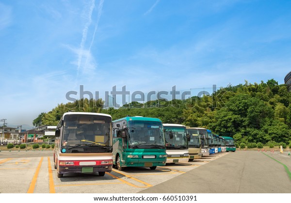 A landscape view of a car park full\
of many buses, sunny day, clear sky. Fukuoka,\
Japan.