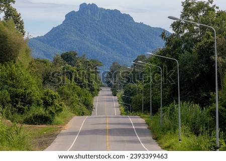 Landscape view of countryside, Curve or wave of slopes and hilly road with big mountain as background, Causeway or highway in Mueang Pan district and Chae Son National Park, Lampang province, Thailand