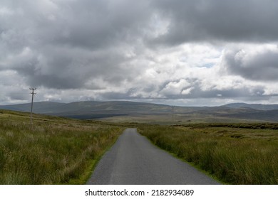 landscape view in County Donegal under an overcast sky with a small country road leading to the horizon - Shutterstock ID 2182934089