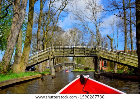 landscape and view of Giethoorn village in Netherlands (Holland) near Amsterdam, canal boat trip and old typical and traditional vintage thatched houses (cottage), famous attraction, destination. 