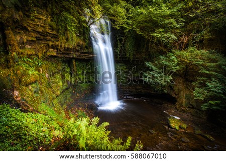 A landscape view of Glencar waterfall outside of Sligo, Ireland with green foliage