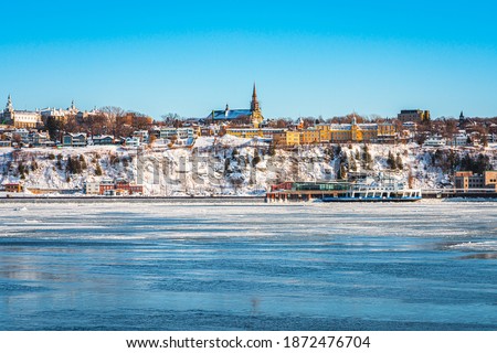 Landscape view of Levis City on south shore of St Lawrence river by ferry boat crossing connects Quebec city and Levis, Canada. Beautiful winter cityscape with snow covered buildings, trees and river.