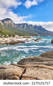 Landscape view of ocean beach, sea, clouds, blue sky with copy space on Camps Bay, Cape Town, South Africa. Tidal waves washing on shoreline rocks or boulders. Background of Twelve Apostles mountains