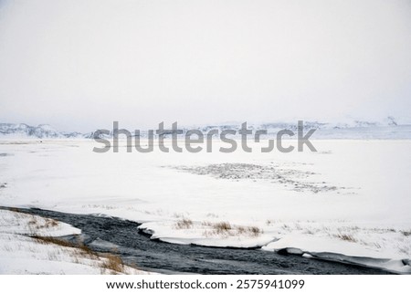 Landscape view of river flow with snow covered fields and mountain ranges in Iceland. Nature, travel, winter background, or wallpaper