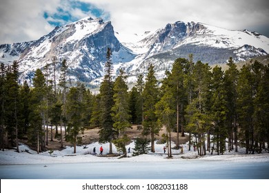 Landscape view of Rocky Mountains National Park in Colorado with trees in the foreground and mountains in the background.