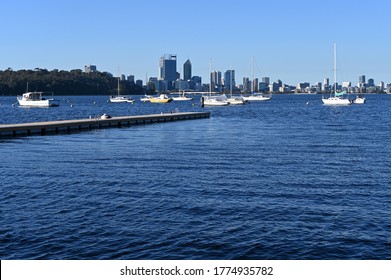 Landscape View Of Sail Boats Mooring In Matilda Bay On Swan River Against Perth Financial District  Skyline In Western Australia.