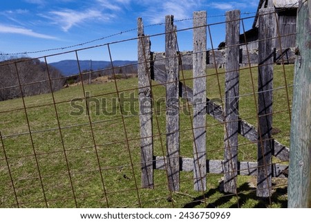 landscape view and section of an old barn can be seen through the wire fence and wooden open gate in rural Virginia,
