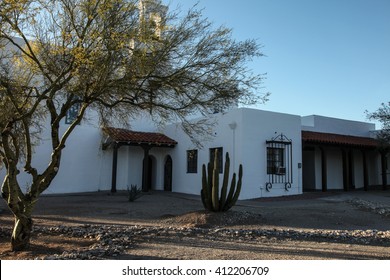 Landscape view of sunlight on tall grooved spiny upright arm of isolated wild desert Organ Pipe cactus in Catholic church's foreground courtyard shade in tourism town Ajo, Arizona USA