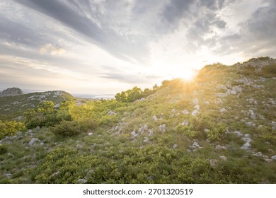 A landscape view of the Velebit Mountain range with the sun shining in the background