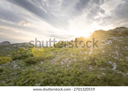 A landscape view of the Velebit Mountain range with the sun shining in the background
