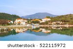 Landscape of village Ston in Dalmatia, Croation. Houses with red roofs reflecting in the water. There are mountains in the background
