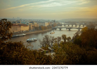 landscape with Vltava river, Charles Bridge and boat at sunset in autumn in Prague, Czech Republic.