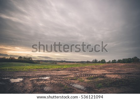 Landscape with wheel tracks on a muddy field in autumn in cloudy weather in off-road terrain