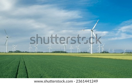 Landscape with a windmills park on the North Sea coastline, in Schleswig-Holstein, Germany. Windmills and agricultural fields on a sunny day