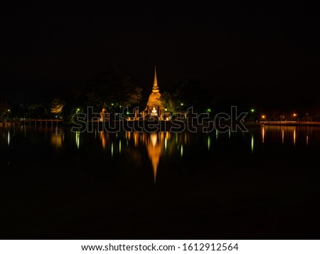 landscape yellow pagoda with waterreflection  in the night at Thailand