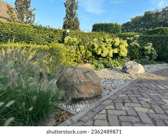 Landscaping with boulders. Flower bed with ornamental grass, hydrangea and boulders on pebbles