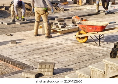 Landscaping company contractors working on interlock driveway project construction site and paving stone bricks. Men working as team to design and construct large home landscape business project.