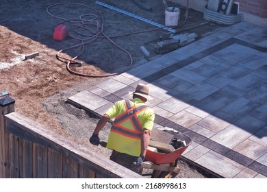 Landscaping Contractor Worker Working On A Backyard Construction Site For A Paver Patio Interlock Project. 