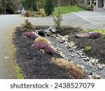 Landscaping of a drainage ditch running through a driveway culvert, water meter in view