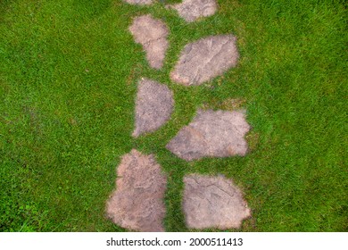 Landscaping Of The Garden Path Of Natural Rough Stone Along Which To Walk To Backyard And Go To The House On Summer Green Lawn Top View Texture With Space, Nobody.