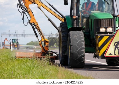 Landscaping And Grounds Maintenance. Tractor Crew With Mechanical Mower Mowing Grass On The Side Of Asphalt Road