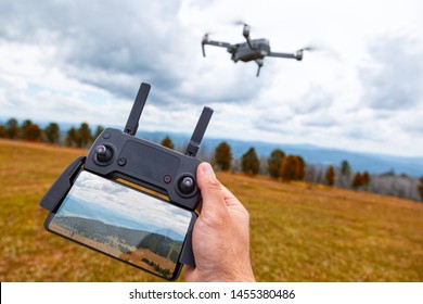 Landscaping on a quadcopter. A young man holds in his hand a quadcopter control panel with a monitor and an image of mountains