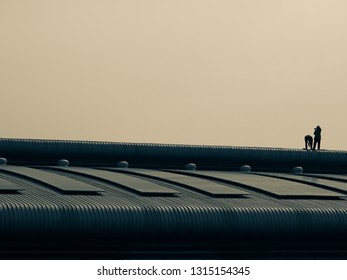 Landscaping, two technicians are installing solar panels on the factory roof, vintage tone style