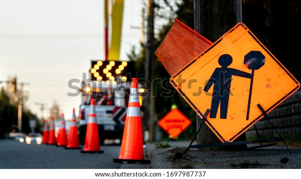 Lane closure on a busy road due to maintenance,\
signs detour traffic temporary street work orange lighted arrow,\
barrels and cones.