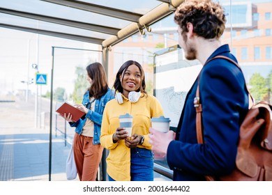 Language barrier concept. Handsome caucasian man offering coffee to an attractive positive african american woman at bus stop outdoor. How acquaintances with man concept. - Shutterstock ID 2001644402