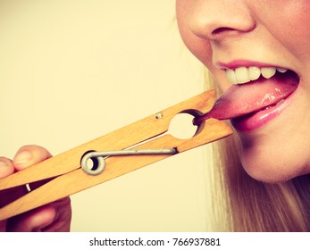 Language barrier, rumors, problems with expressing concept. Blonde woman having tongue in clothespin